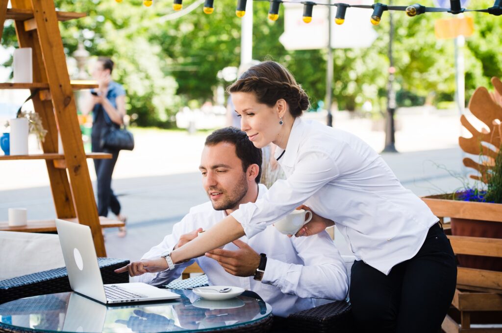 man and woman working on laptop at outdoors cafe during the break